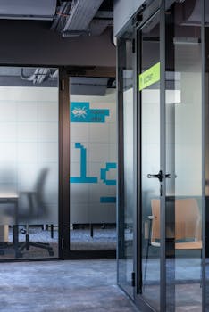 Contemporary office interior with glass walls, open layout, and modern furnishings.