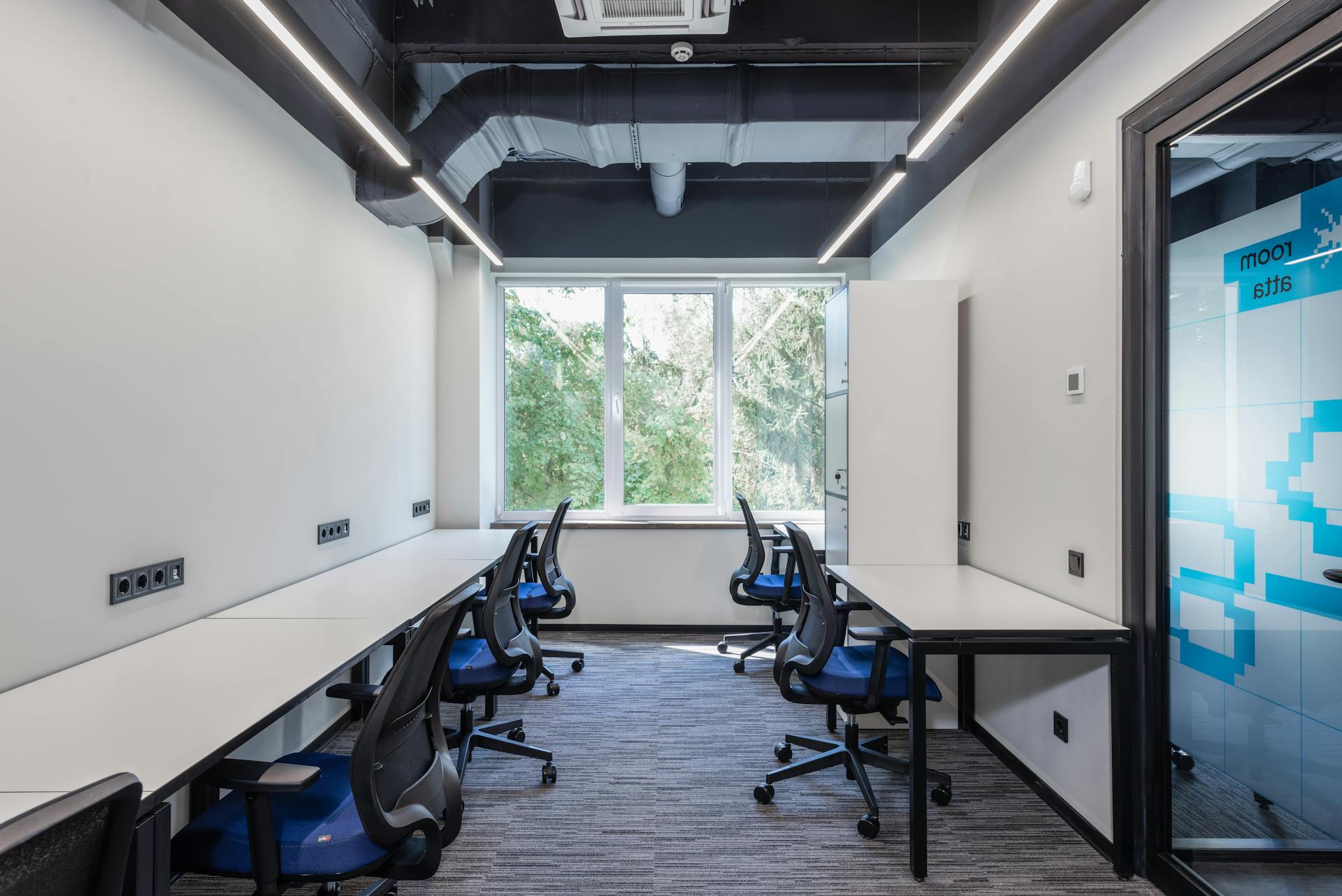 Contemporary open space office with white tables and armchairs placed near glass door and big window in creative business center