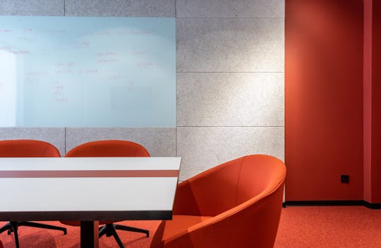 Stylish contemporary conference room with red chairs and whiteboard wall.