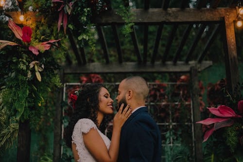 Couple Under Garden Arch Surrounded With Flowers