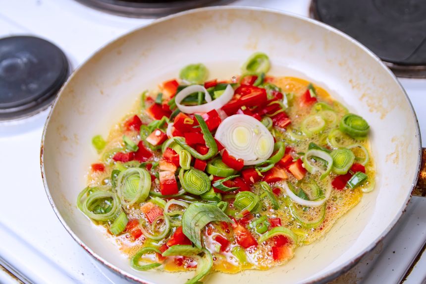 Sliced peppers softening in a pan — photo by Nikola Cvetkovic on Pexels