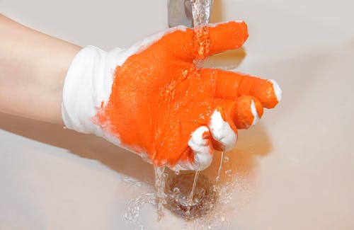 Close-Up Photo of a Person's Hand with a White and Orange Glove