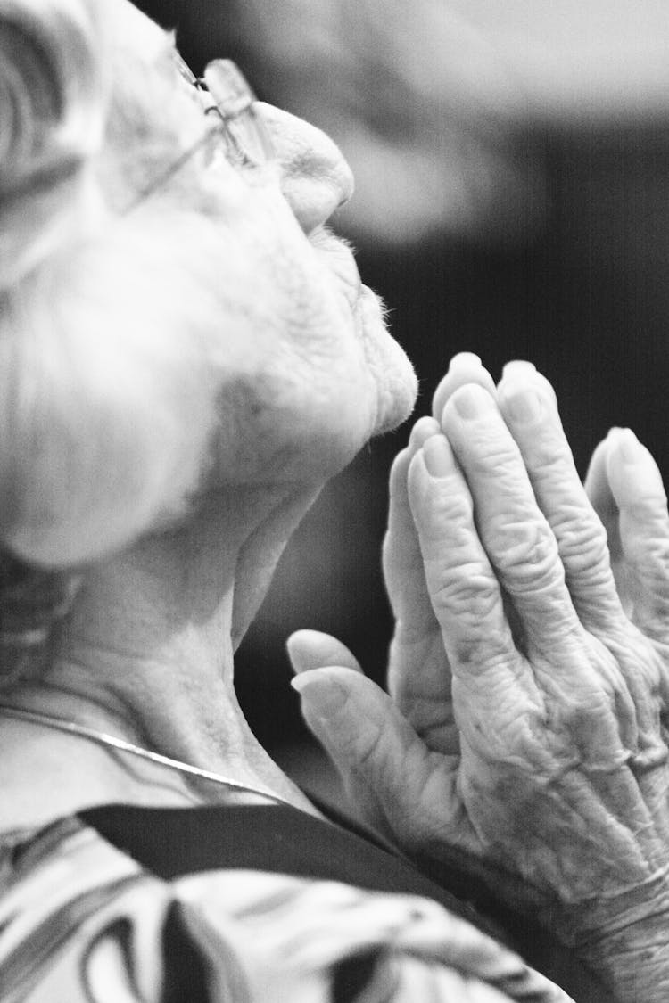 Grayscale Photo Of An Elderly Woman Praying