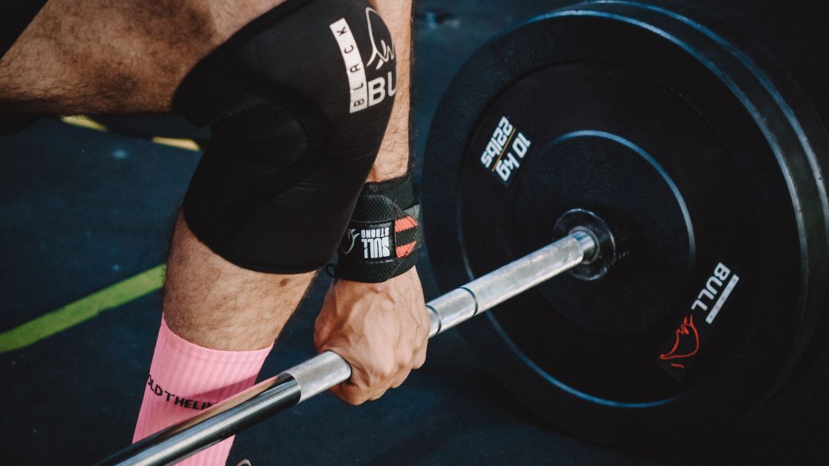 Close-up of a man performing deadlifts with heavy weights in a gym.