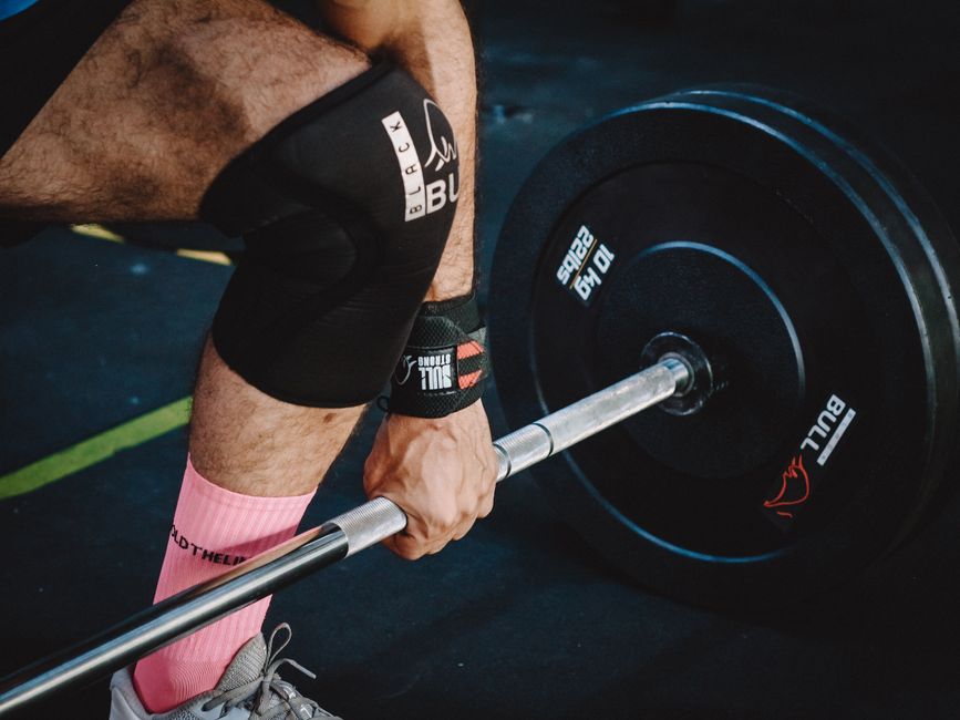 Close-up of a man performing deadlifts with heavy weights in a gym.
