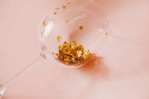 Free Close-up of a Wineglass with Gold Confetti Inside  Stock Photo