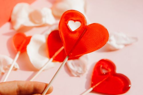 Free Red heart-shaped lollipops with white petals on a pink backdrop, perfect for romantic themes. Stock Photo