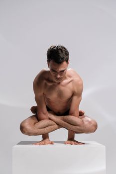 Athletic man in advanced yoga pose showcasing balance and strength indoors.