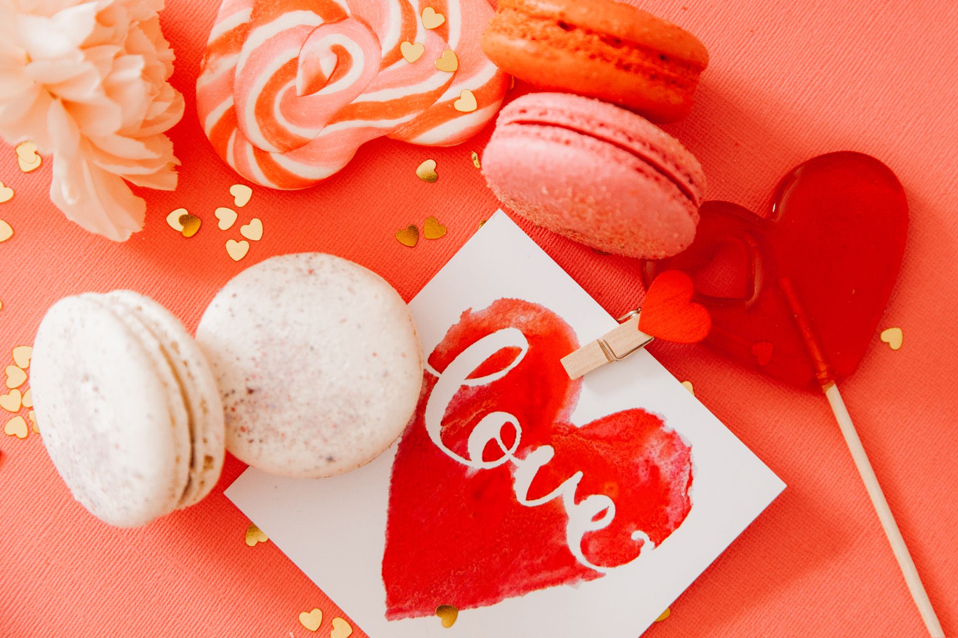 Top view of assorted sweets and a love card on a pink background, perfect for Valentine's Day.
