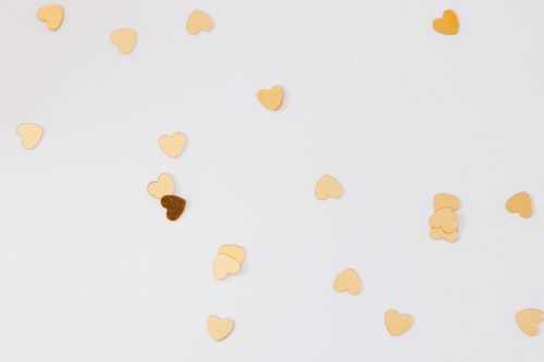 Free Gold heart-shaped confetti scattered on a white background, perfect for celebrations and parties. Stock Photo