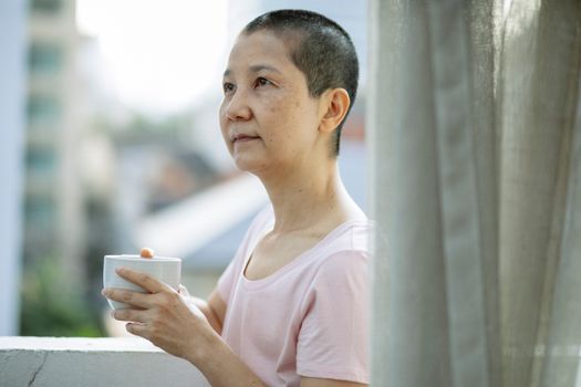 Adult pensive ethnic woman drinking coffee on terrace