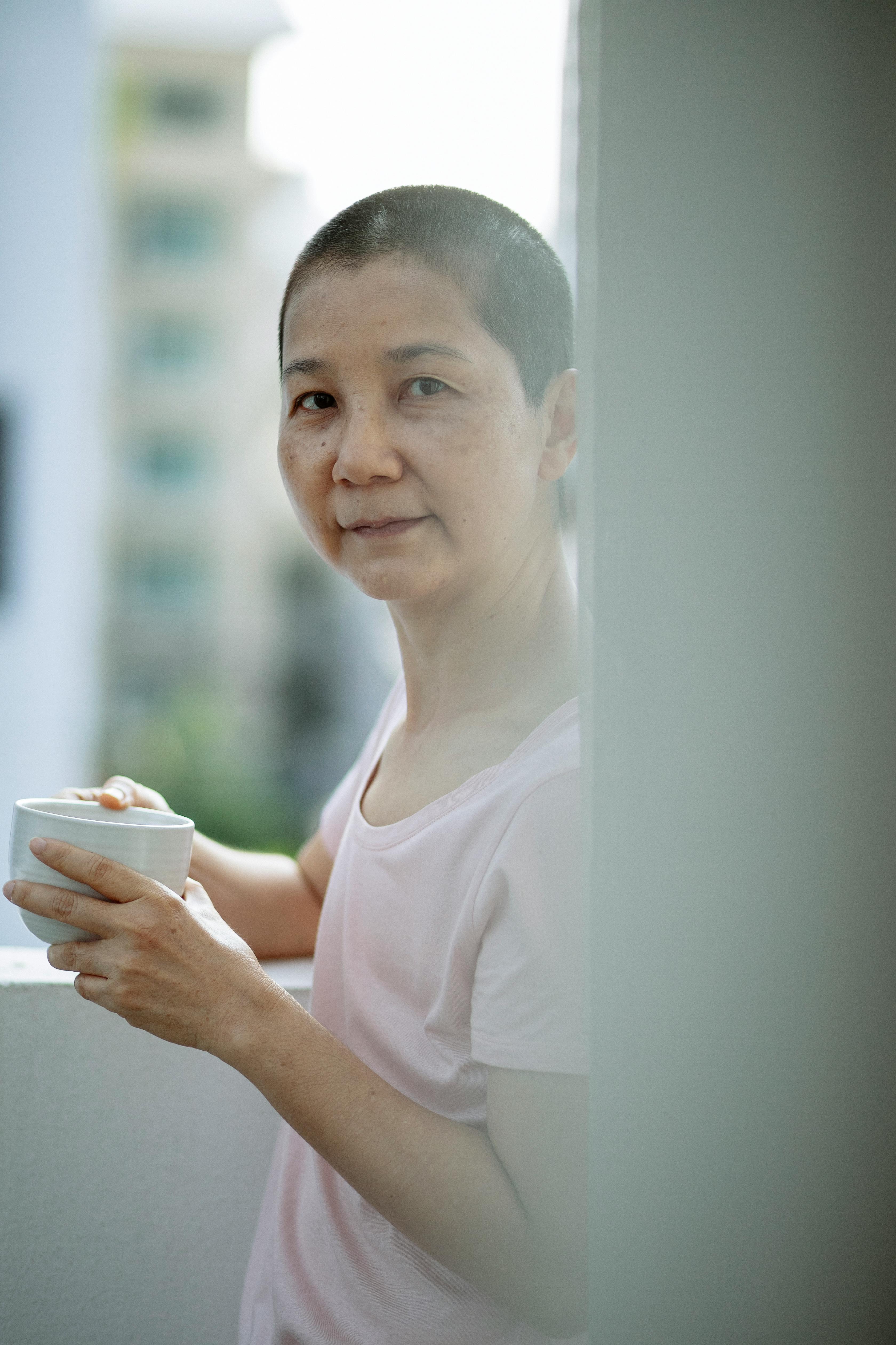 adult ethnic woman drinking coffee and looking at camera on balcony