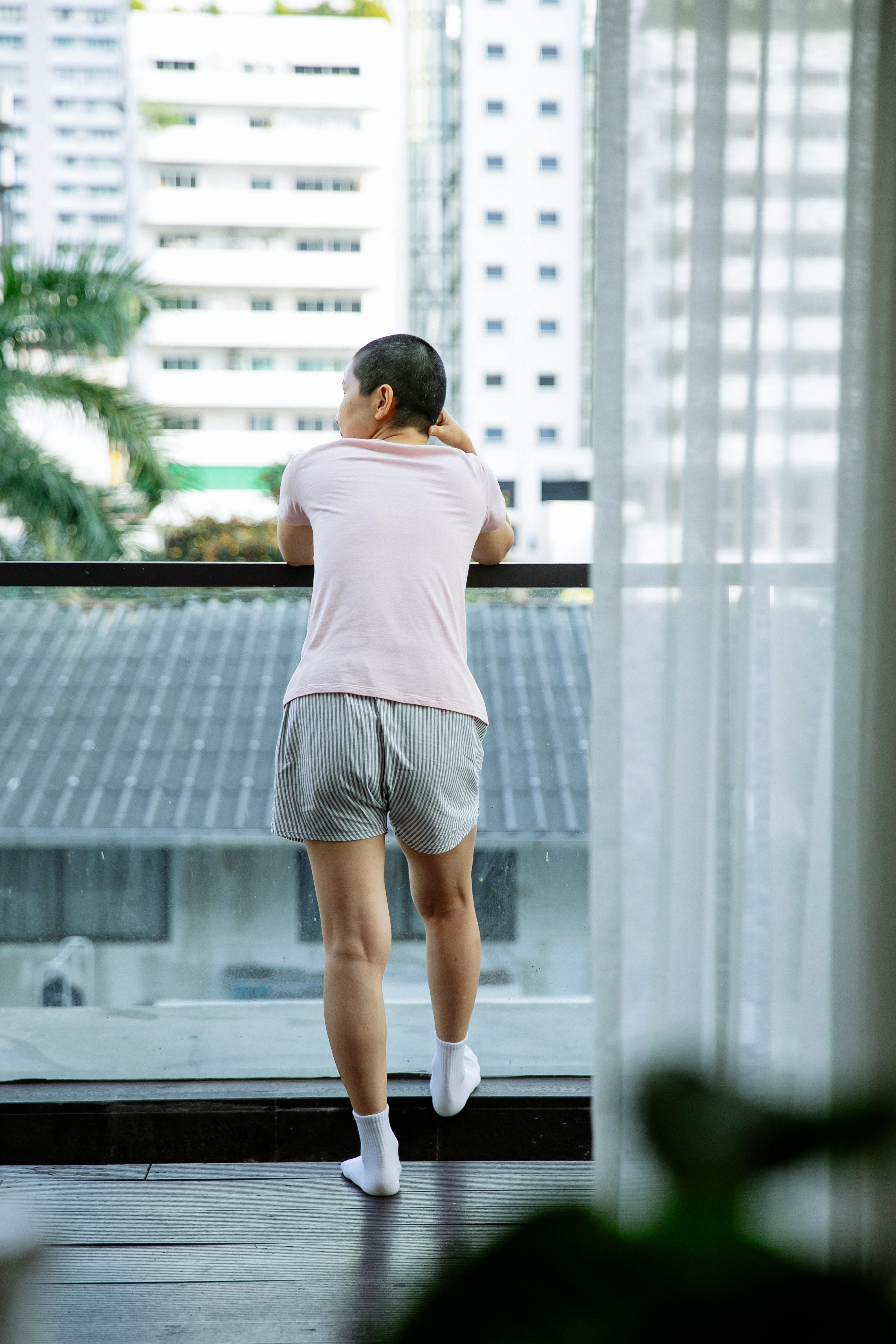 slender woman with cancer on glass balcony of hospital