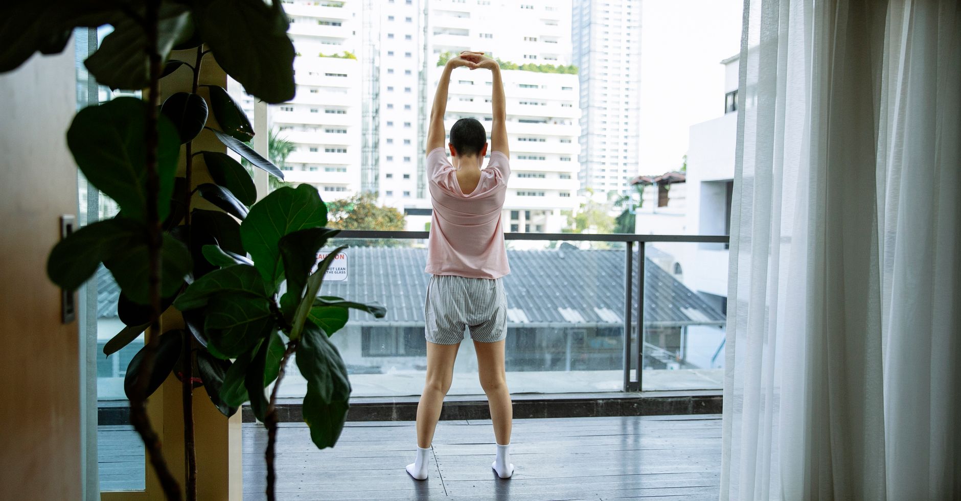 Back view of anonymous short hair female with cancer warming up on balcony of hospital in daytime