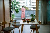 Back view of anonymous female with short hair in pink robe suffering from cancer in comfortable apartment with balcony