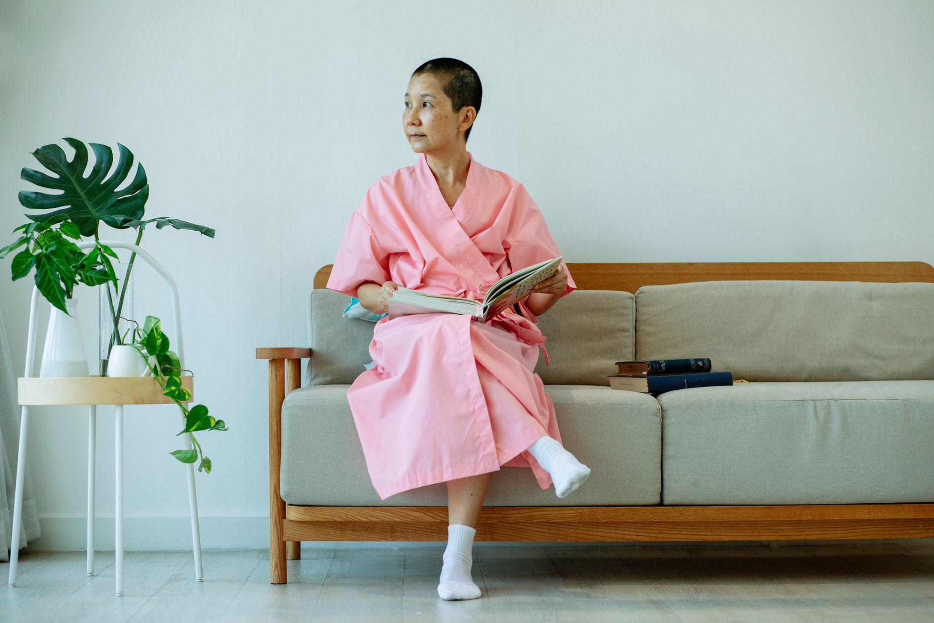 Serene middle-aged woman in a pink robe reading indoors on a cozy sofa.