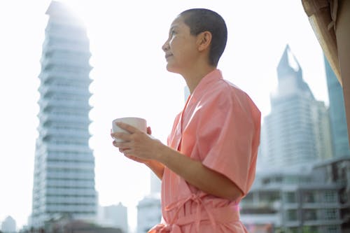 Short haired happy Asian woman with breast cancer enjoying tea