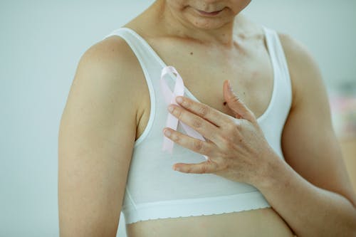 Crop woman in white underwear holding pink ribbon