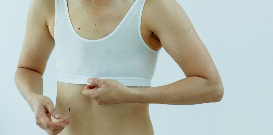 Crop anonymous female after breast removal surgery wearing light white bra against white background