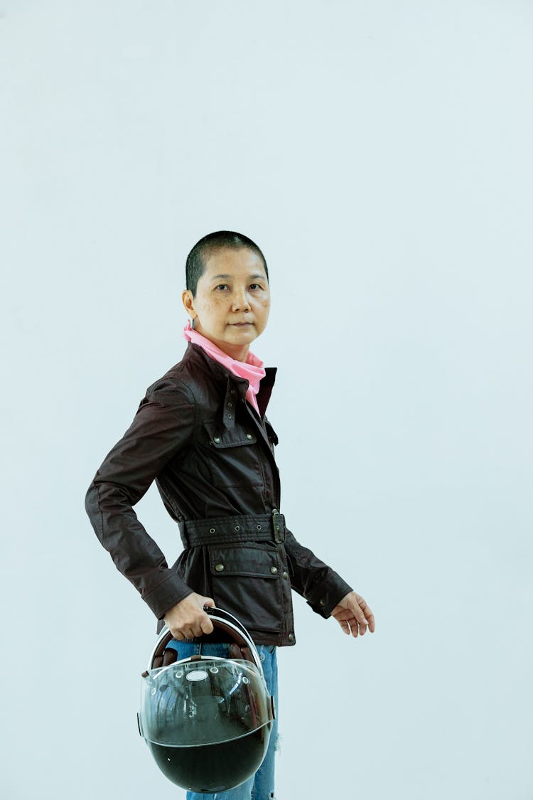 Senior Asian Woman Standing With Motorcycle Helmet And Looking At Camera