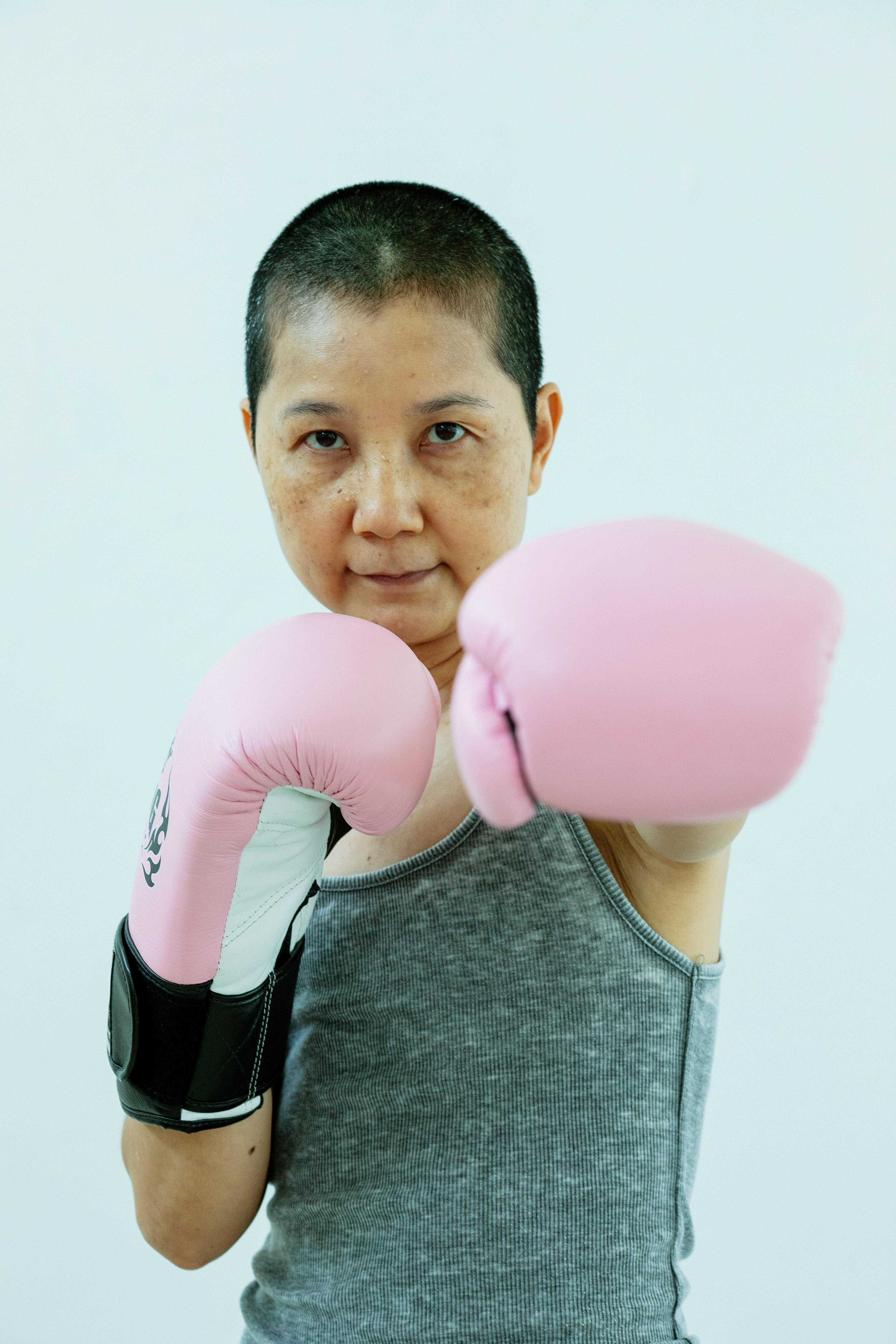 asian woman in pink boxing gloves in studio