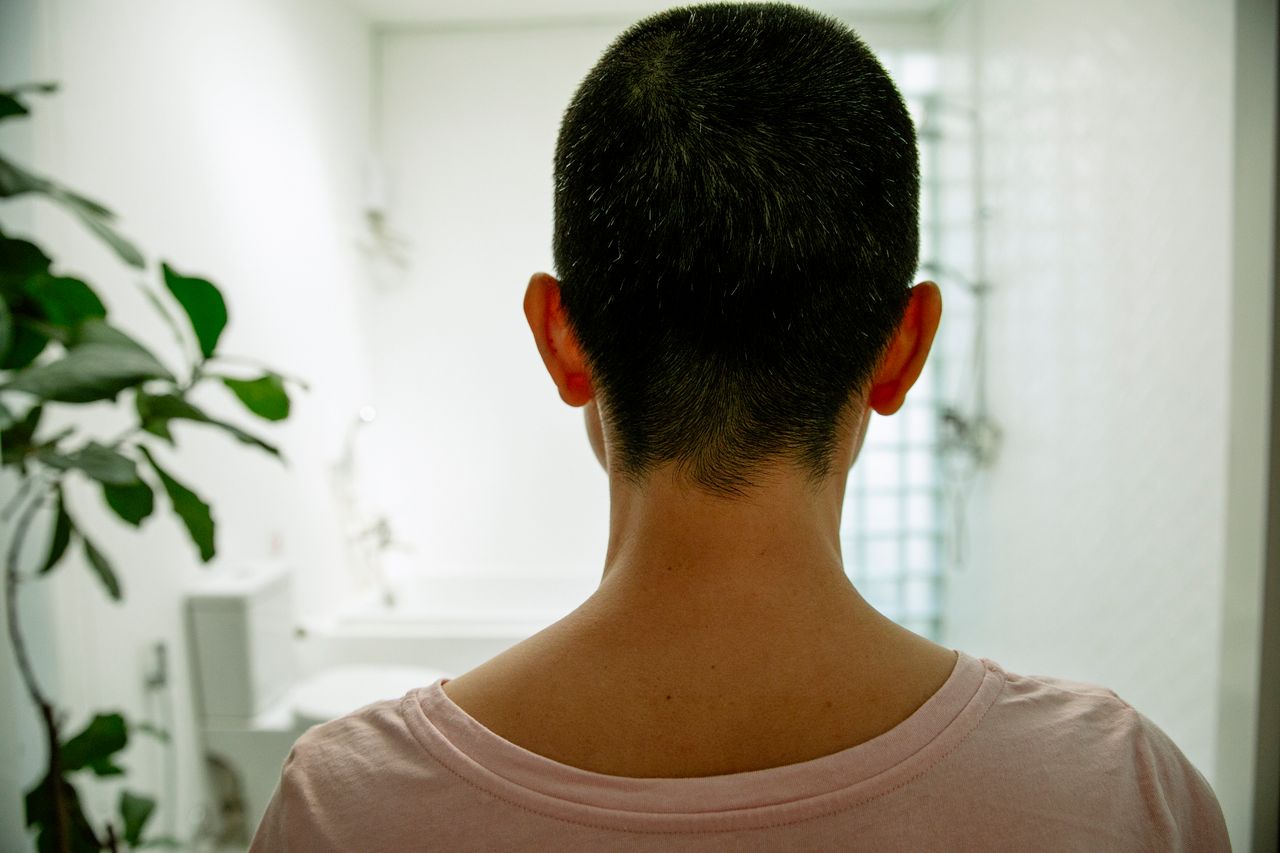 back view of unrecognizable lady in t shirt standing in bathroom with