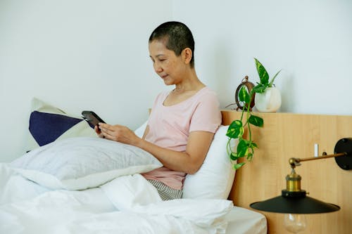 Serious Asian female surfing on phone in bed