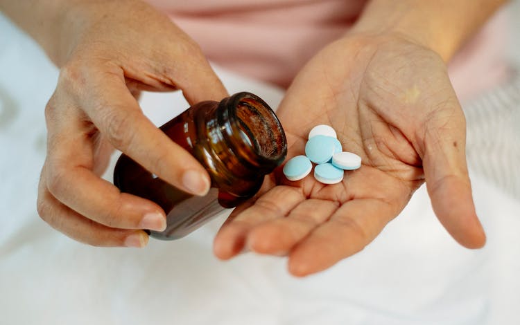 Anonymous Female With Pills In Hand And Bottle