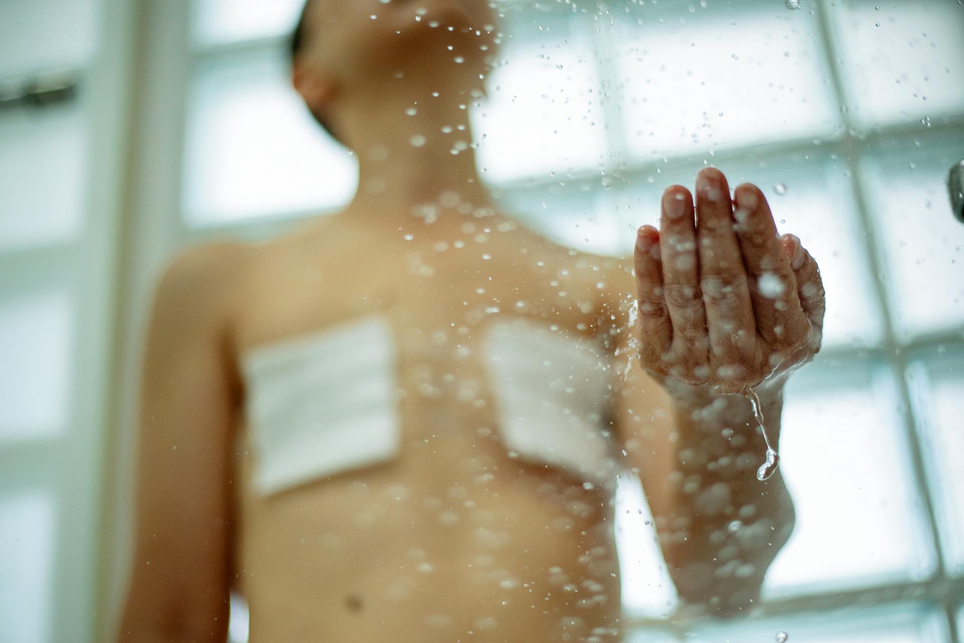 Woman with bandages on breast after surgery taking shower