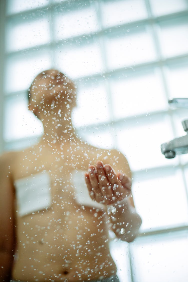 Woman With Breast Cancer Catching Drop Of Shower In Bathroom