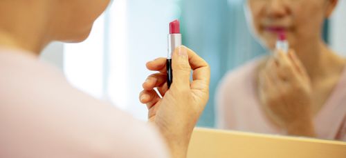 Free Crop faceless serious middle age female in casual outfit with purple lipstick looking at mirror reflection in bright apartment Stock Photo