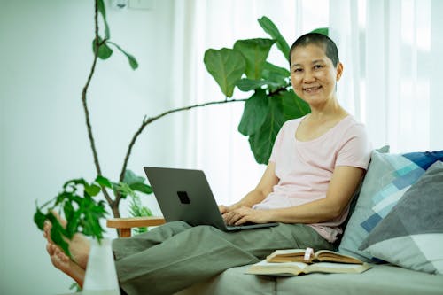 Free Happy Asian lady using netbook on couch in living room Stock Photo