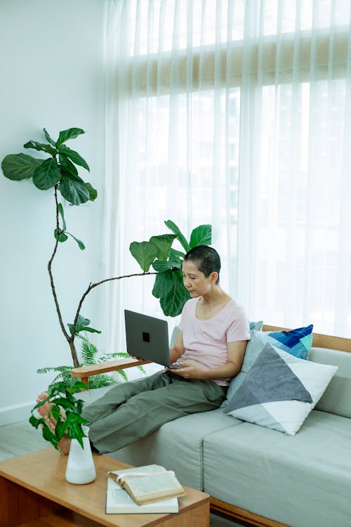 Serious ethnic woman surfing on laptop on sofa at home