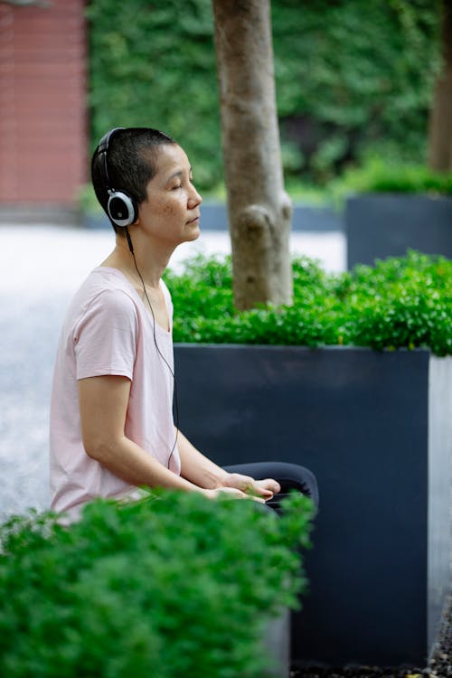 Ethnic female on bench in headphones in park