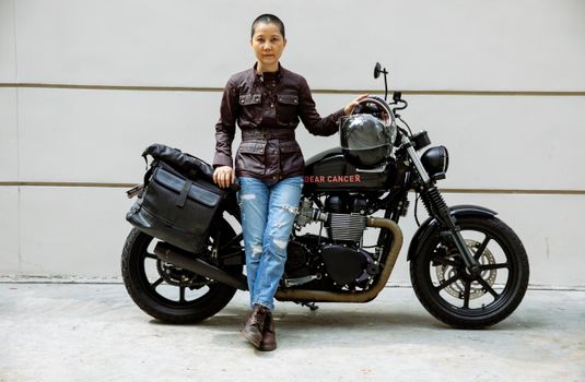 Serious Asian lady near motorcycle in street on road