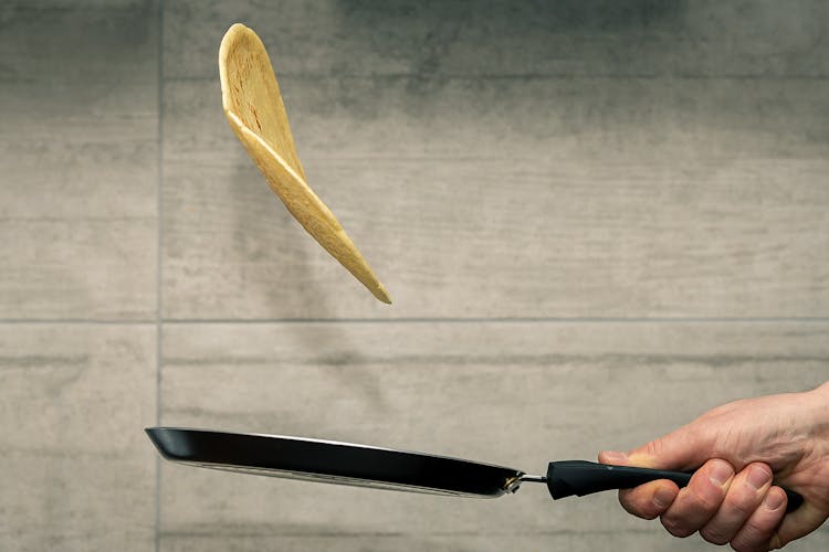 Close-Up Photo Of A Person Flipping A Piece Of Bread On A Pan 