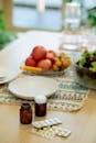 Jars of medicines and pills placed on table near fruits