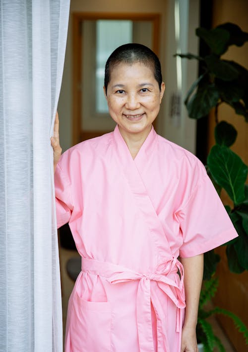 Positive Asian woman in pink robe suffering from breast cancer