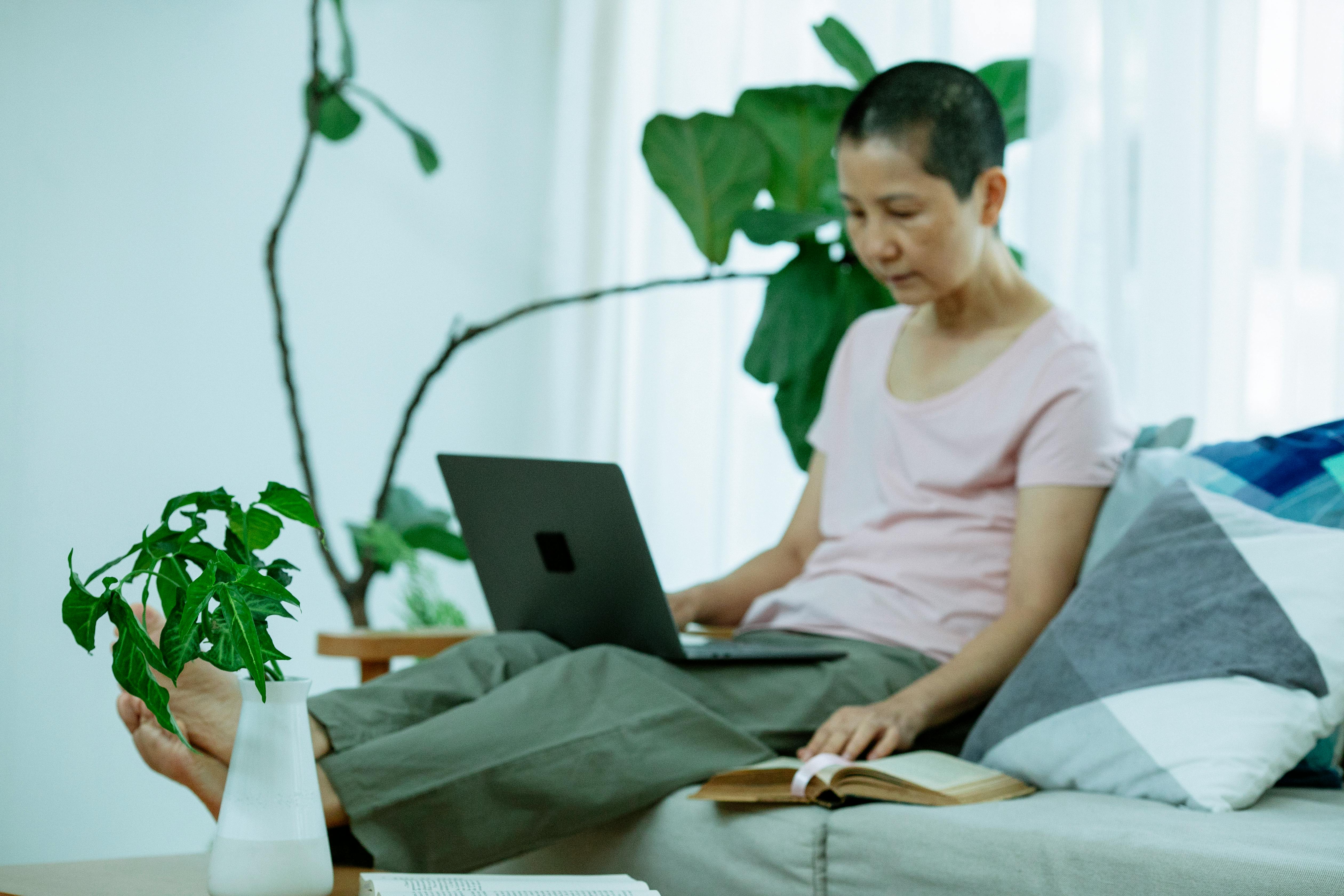 focused self employed asian woman using netbook on couch at home