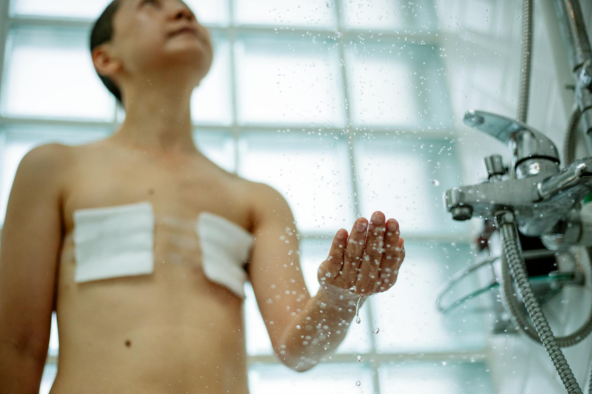 Asian woman post-mastectomy enjoying a refreshing shower, symbolizing recovery and wellness.