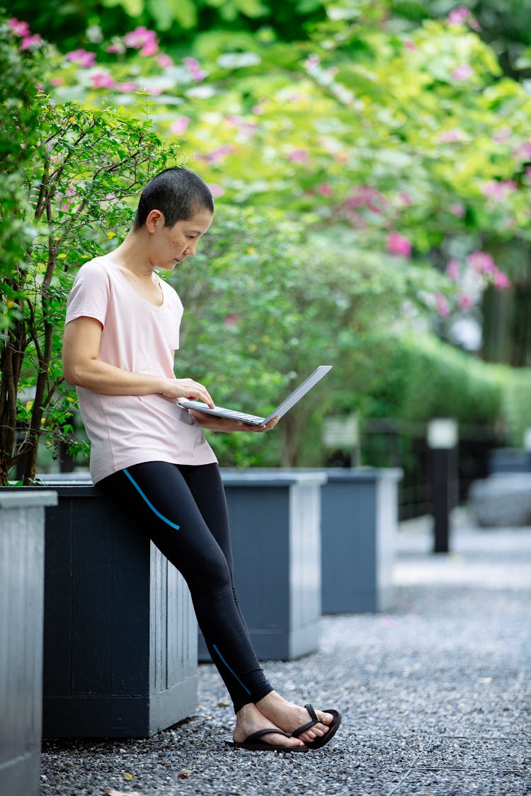 Serious Self Employed Ethnic Woman Using Laptop In Garden