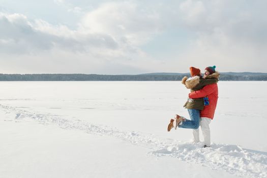 Couple hugging in a snowy outdoor scene, showcasing love and warmth in winter.