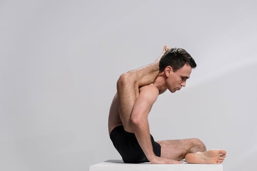 A man demonstrating an advanced yoga pose indoors, showcasing flexibility and concentration.