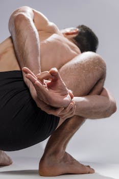 Man performing a challenging yoga pose, captured from a low angle indoors.