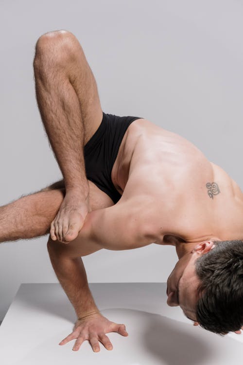 A Topless Man Doing an Acrobatic Exercise