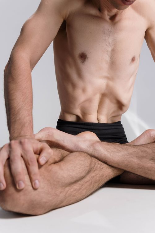 Free A shirtless man meditating in a lotus position on a white background, focusing on wellness. Stock Photo