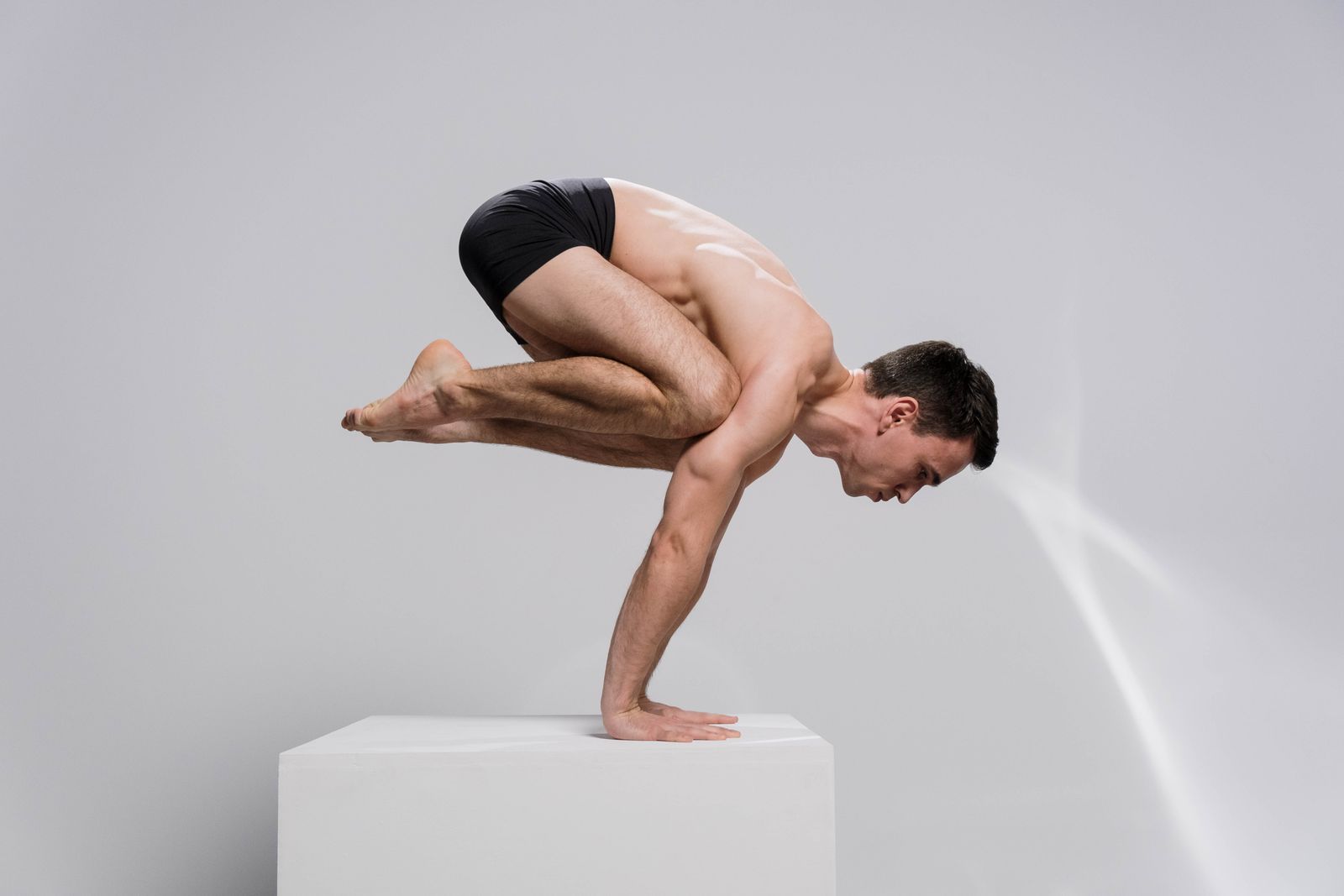 Man in a powerful arm balance yoga pose demonstrating strength and control typical of power yoga