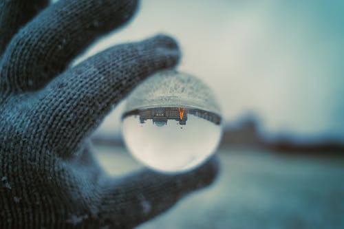 Close-up of a Person Holding a Glass Ball Reflecting the Landscape Upside Down 