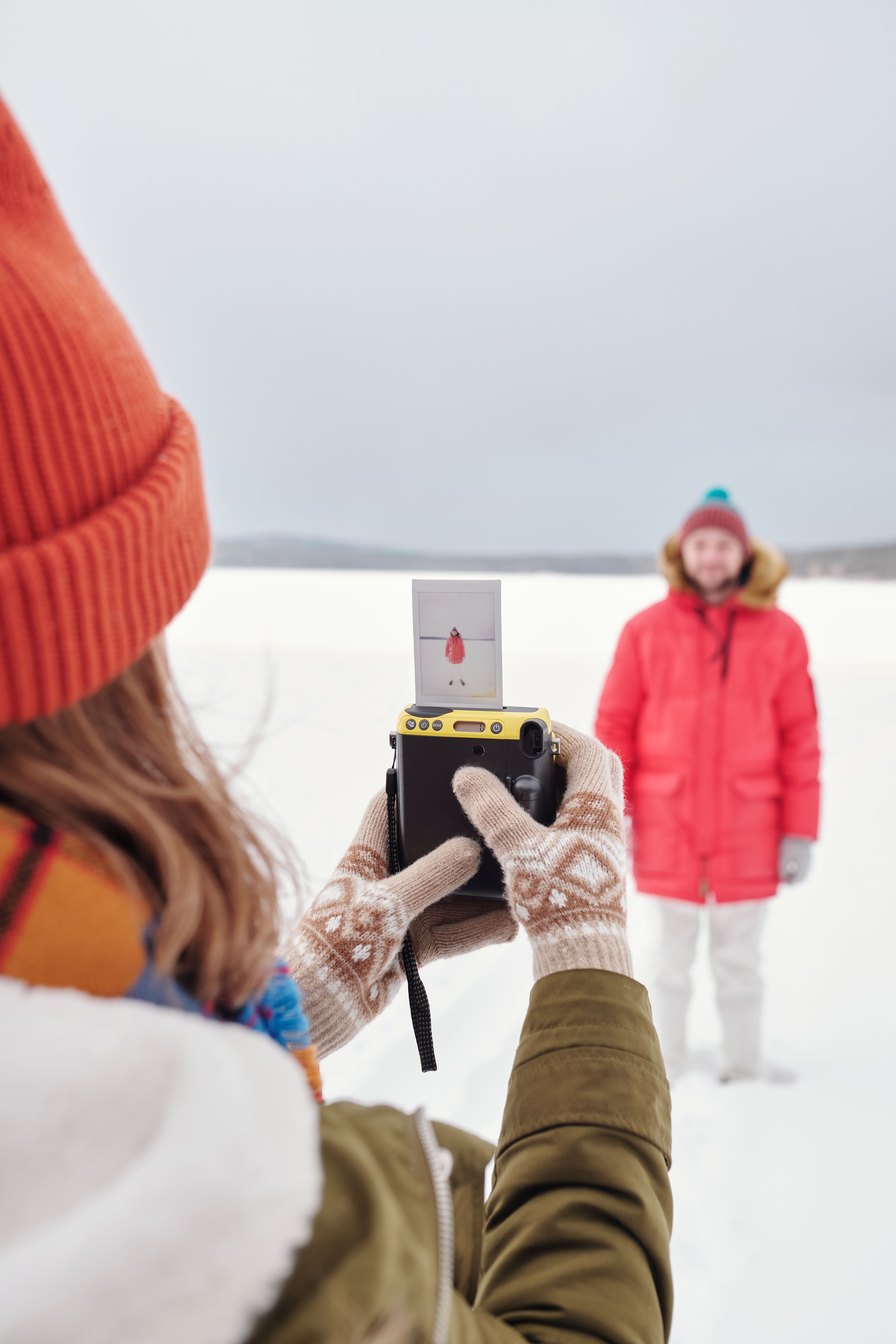 Free Person capturing a photo in snow-covered landscape with an instant camera. Stock Photo