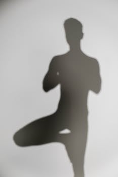 Abstract shadow of a person meditating in yoga pose on white background, promoting wellness and mental health.
